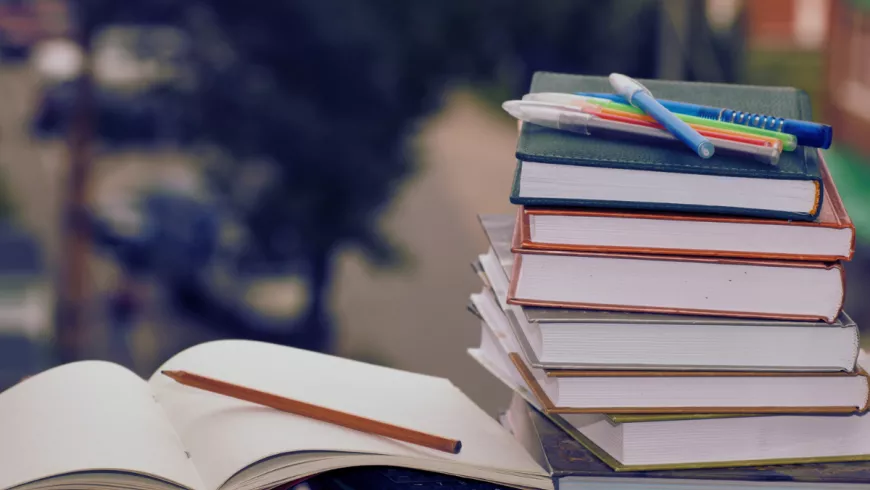 a stack of textbooks next to an open notebook 