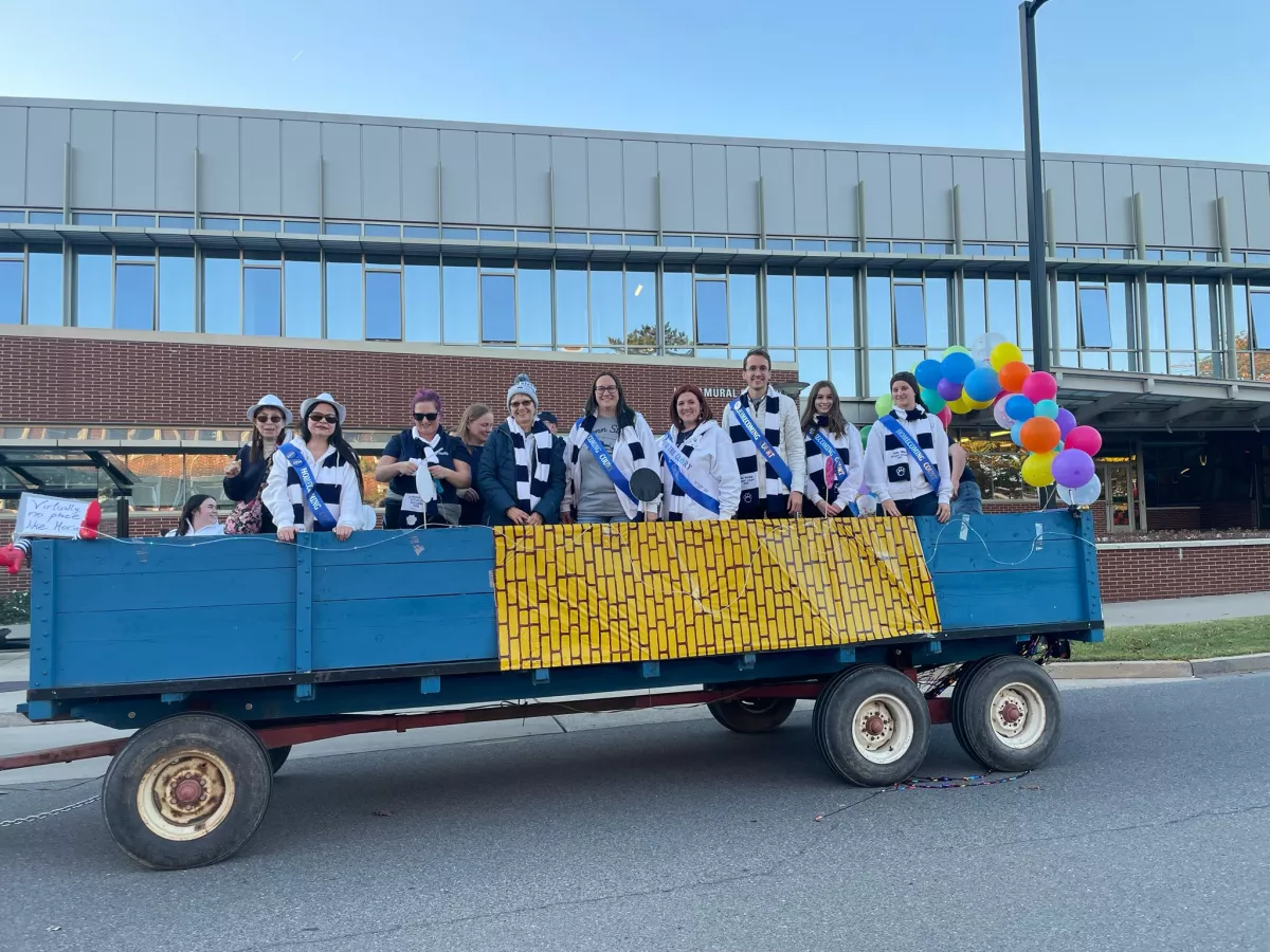 Students wearing Penn State gear riding on a float in the Homecoming parade