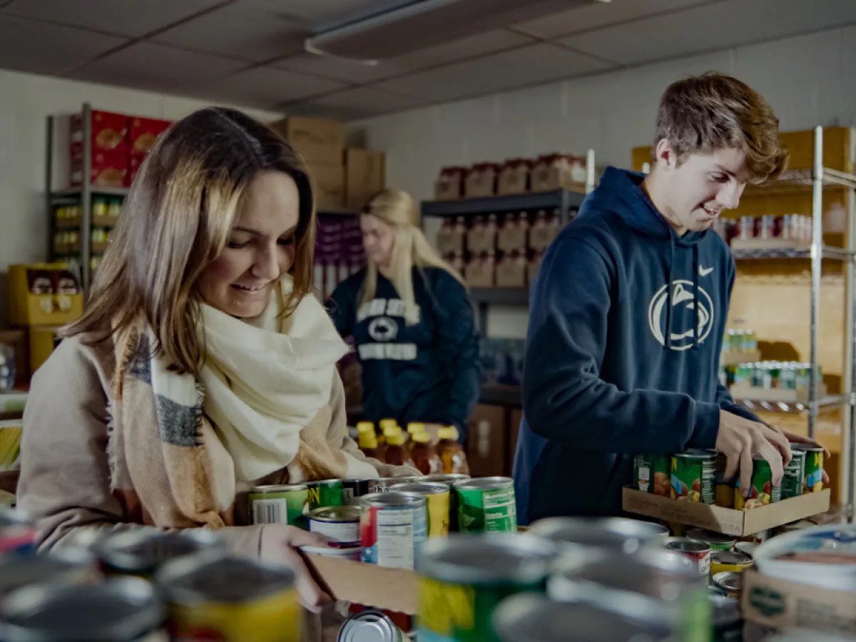 Students - some wearing Penn State apparel - sorting canned goods at a food pantry