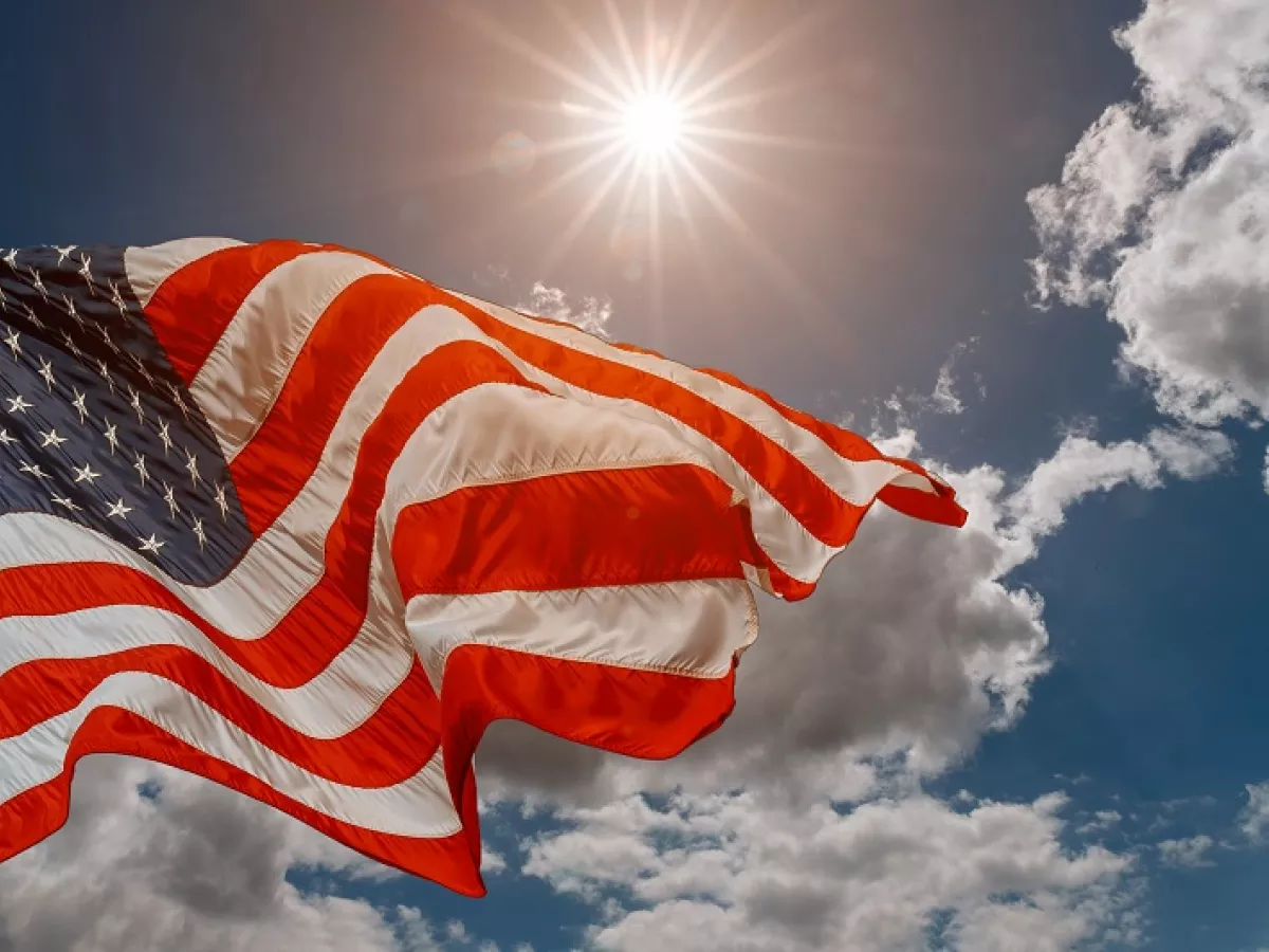U.S. flag flying in front of sun and clouds