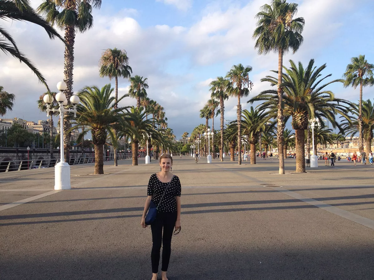 Kate, Penn State World Campus graduate assistant, stands on a street lined with palm trees