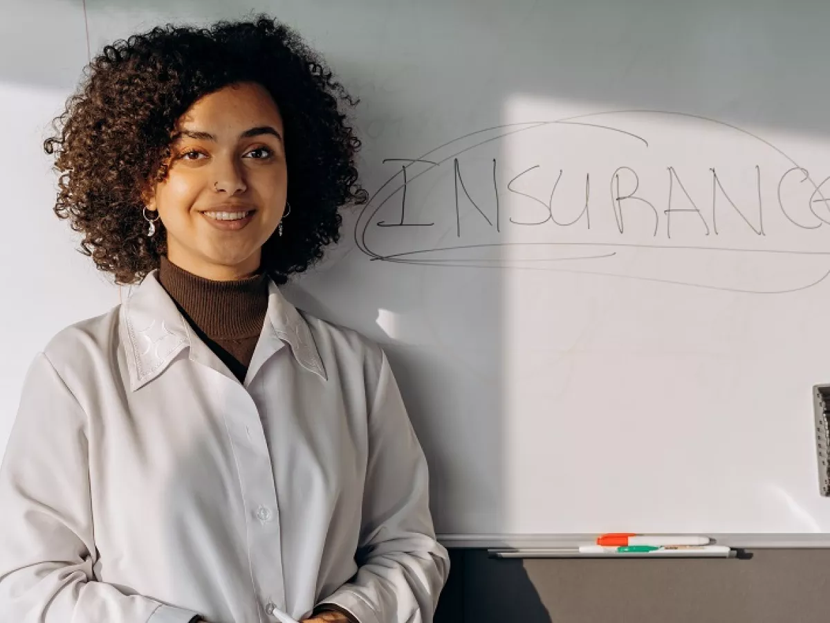 Woman standing in front of white board with the word "insurance" written on it