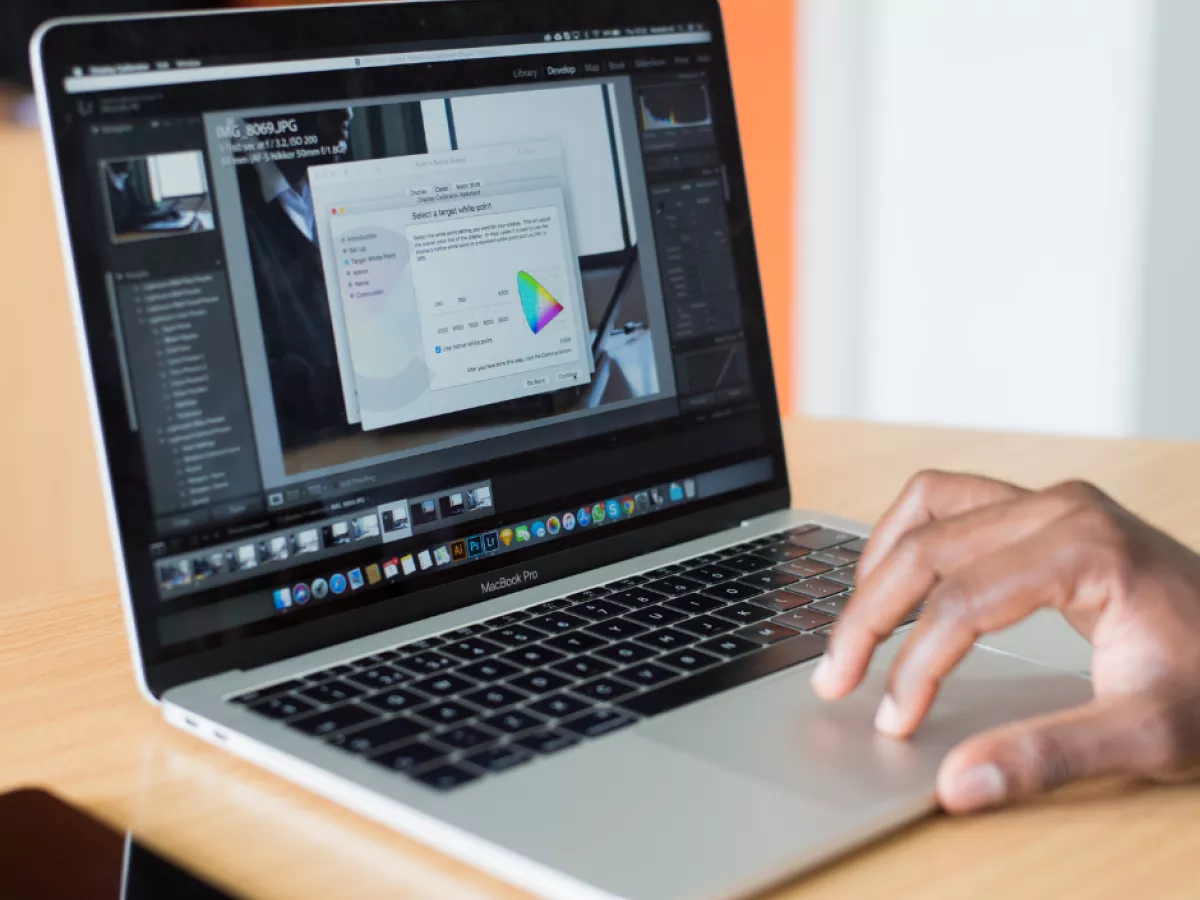Hand on laptop touchpad while multiple windows are visible on the computer screen