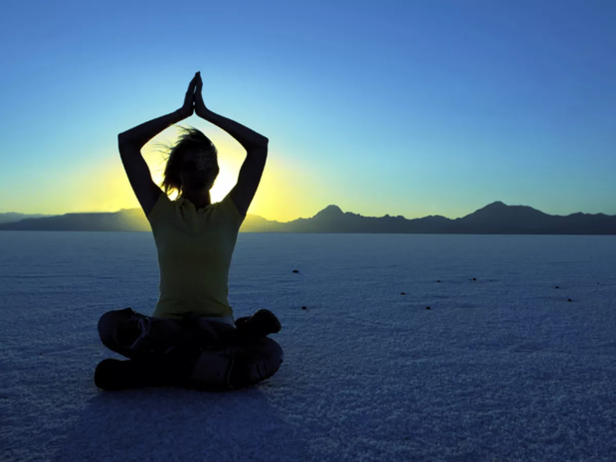 silhouette of a woman meditating on a beach at sunset